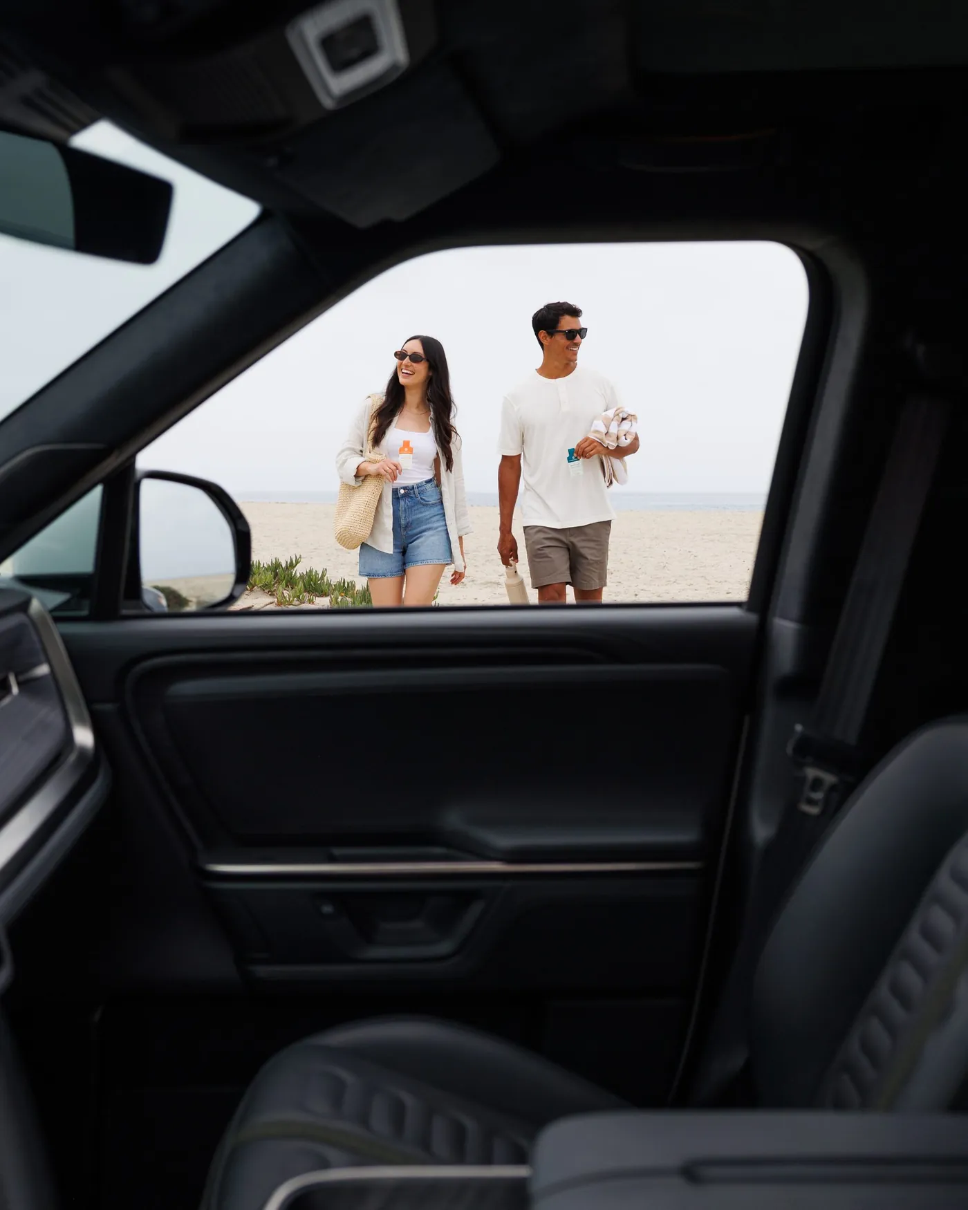 Couple walking from the beach, seen from inside the Rivian